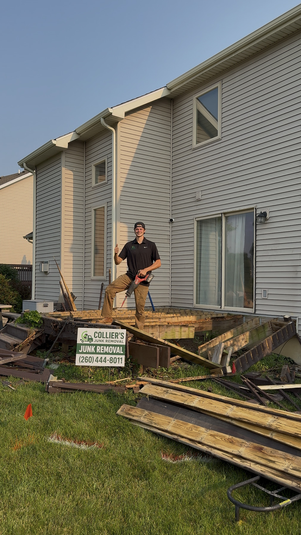 Collier's crew member cutting apart a raised deck with a Collier's yard sign in the foreground