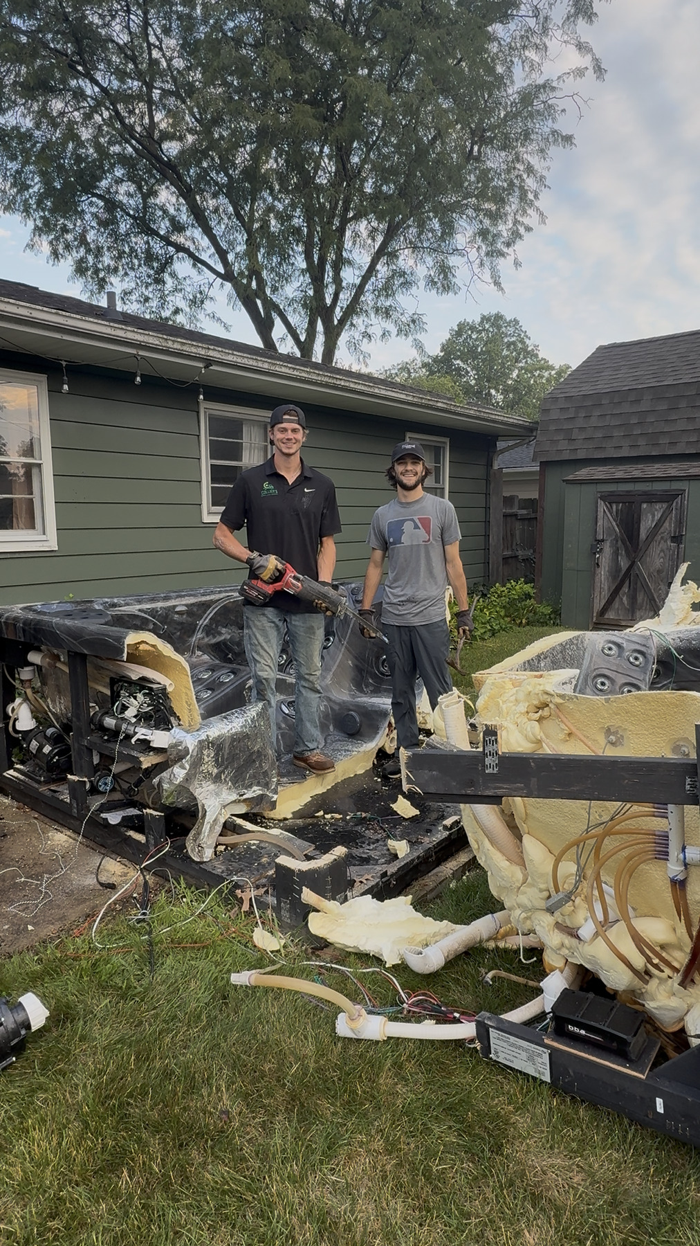 Collier's crew standing over an outdoor hot tub cut into pieces for removal