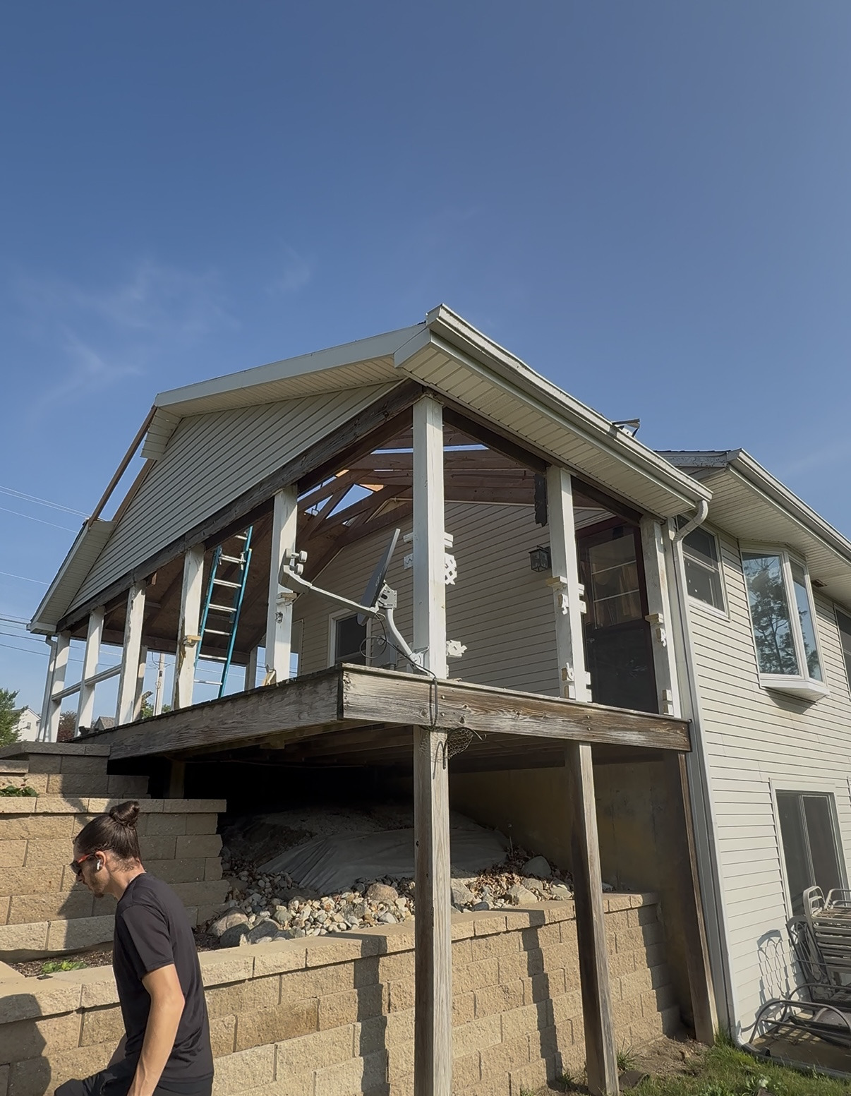 Covered porch being stripped down to its frame above a retaining wall