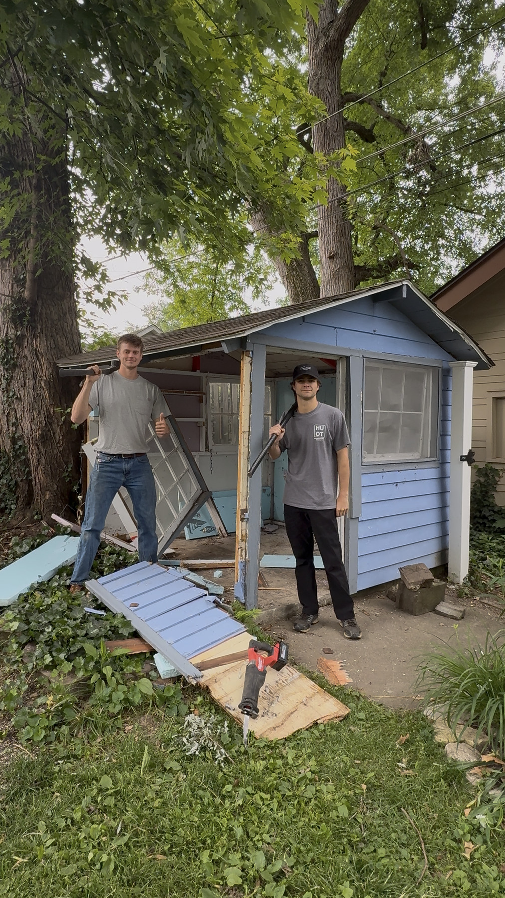 Two Collier's crew members taking apart a backyard shed